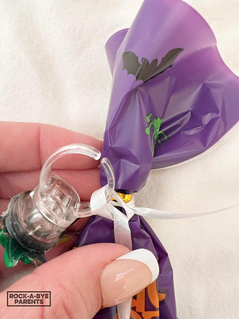 Image showing how to attach the Halloween ring to the white curling ribbon on Halloween treat bag.